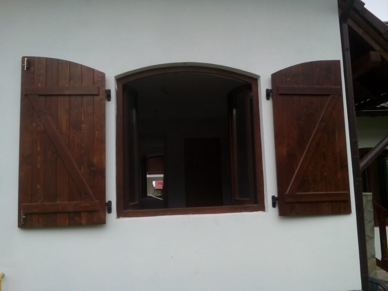 Pereche de obloane din lemn masiv la o fereastră arcuită