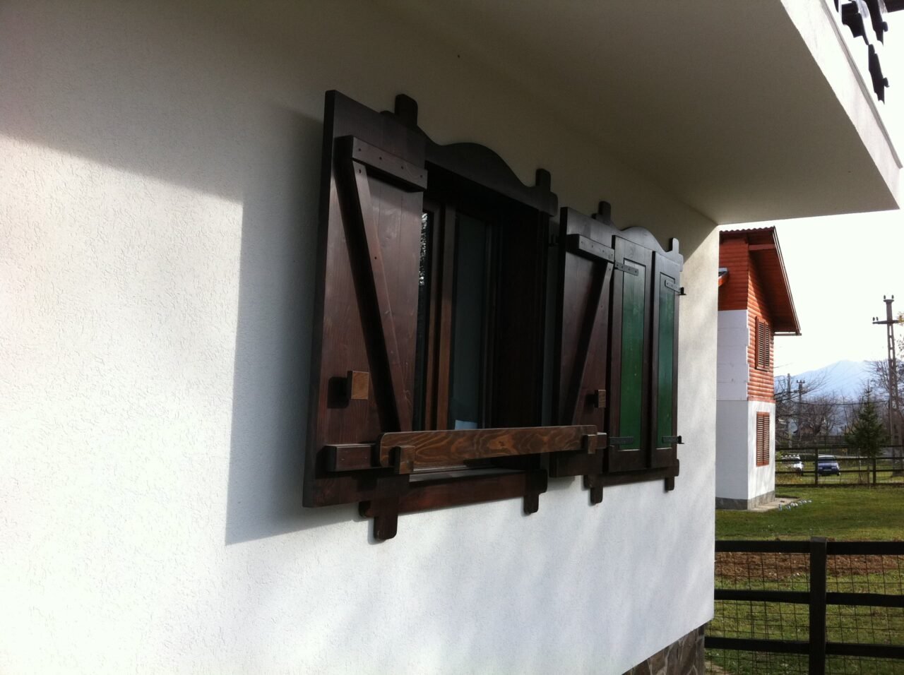 Oblon din lemn masiv închis la culoare, pe o fațadă albă